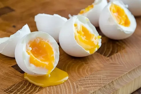 Huevos cocidos partidos con la yema blanda sobre una tabla de madera